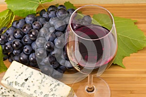 Red wine glass on blurred background of cheese and grapes