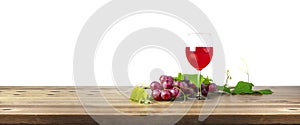 Red wine glass and bunch of grapes on wooden table