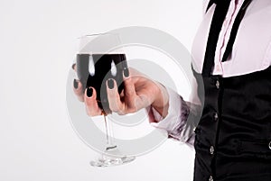 Red wine glass in elegant female hand with black nails