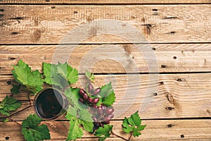 Red wine glass and fresh grapes on wooden background, copy space