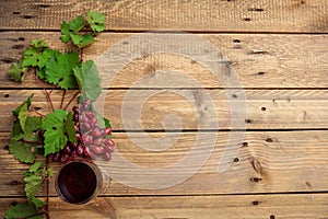 Red wine glass and fresh grapes on wooden background, copy space