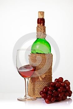 Red wine in glass with grapes and bottle