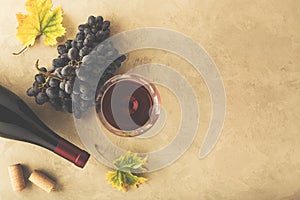 Red wine in a glass, grapes, bottle and cork on the table