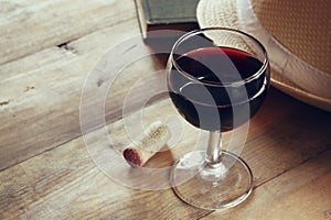 Red wine glass and old book on wooden table at sunset burst. vintage filtered image