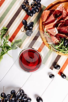 Red wine glass with sliced jamon plate on table background. Top close-up view copy space