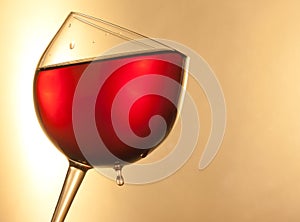 Red wine in the glass tilted with golden drop and space for text