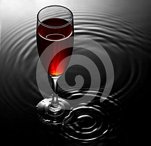 Red wine glass on water ripples background photo