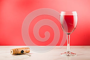 Red wine glass and wooden corkscrew on red background/red wine glass and wooden corkscrew on red background.  Copyspace