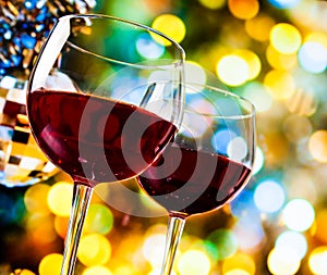 Red wine glasses against colorful bokeh lights and sparkling disco ball background