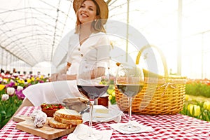 Red wine glasses with defocused young woman in greenhouse on background. Focus on wine glasses