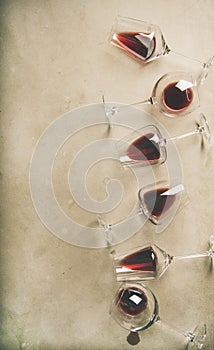 Red wine in glasses over grey concrete background, vertical composition