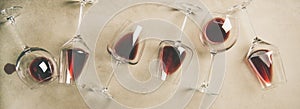 Red wine in glasses over grey concrete background, wide composition