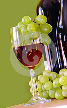 Red wine with grapes cluster over green