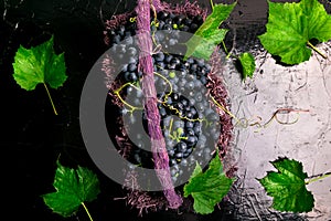 Red wine grapes in voiolet basket on bllack background.