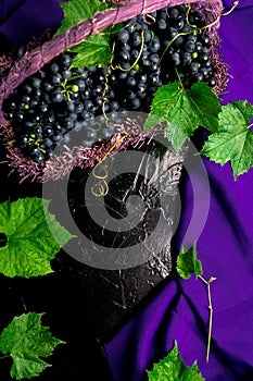 Red wine grapes in voiolet basket on bllack background. Top view. Copy space.