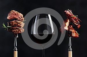 Red wine and grilled meat. Grilled pork belly and beef steak with rosemary on a black background