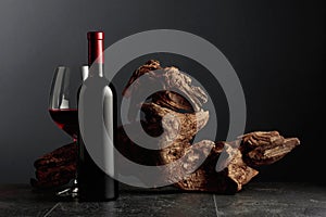 Red wine and old weathered snag on a black stone table