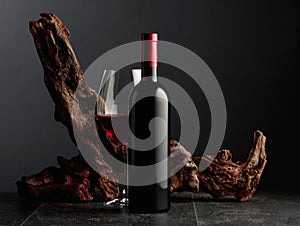 Red wine and old weathered snag on a black stone table