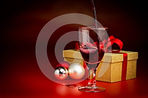 Red Wine Poured Into Glass in Front of Golden Present