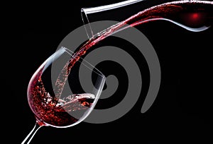 Red wine is poured into a wine glass on a black background