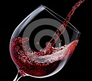 Red wine is poured into a wine glass on a black background