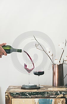 Red wine pouring from bottle into glasses, copy space