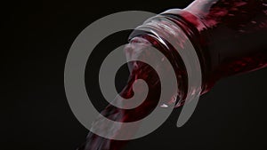 Red wine pouring bottle neck close up. Merlot outflowing in super slow motion.