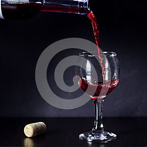 Red wine pouring from the bottle to the glass with splashes