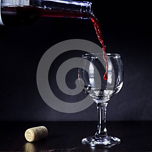 Red wine pouring from the bottle to the glass with splashes