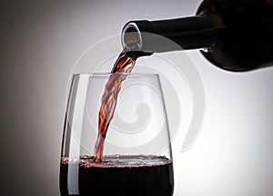 Red wine pouring from the bottle to the wine glass side close up