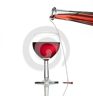 red wine pouring from a bottle in a transparent glass with reflection isolated over white background