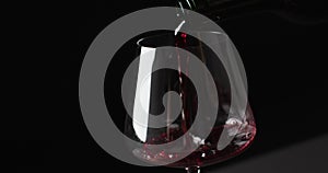 Red wine pouring into glass on black background with copy space