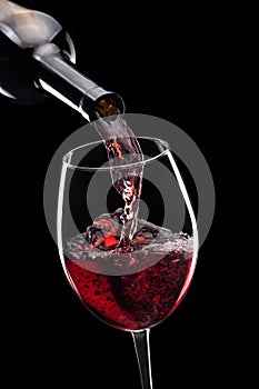 red wine pouring in glass from bottle isolated