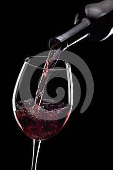 red wine pouring in glass from bottle isolated