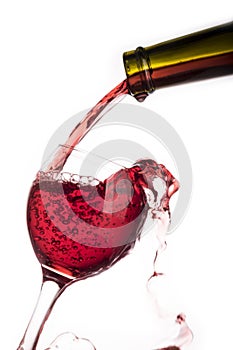 Red wine pouring into the glass from bottle isolated on white background