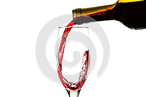 Red wine is pouring into a glass from a bottle