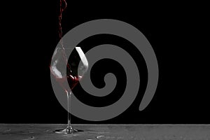 Red wine pouring in glass isolated on black