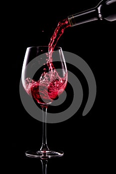 Red wine pouring into glass isolated on black background. Rose wine splashing in glassware.