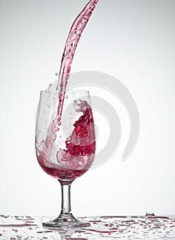 Red wine pouring into glass isolated on white background