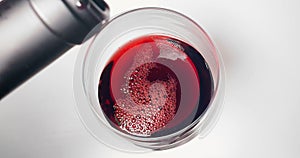 Red wine pouring into glass tilted with top of