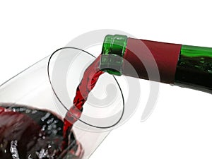 Red wine pouring from green bottle into wine glass isolated on white background