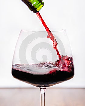 Red wine pouring to the glass close up