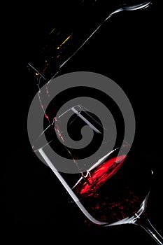 Red wine pouring into wine glass on black