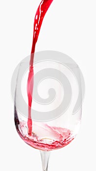 Red wine pours into a tall glass