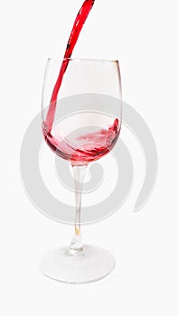 Red wine pours into a tall glass