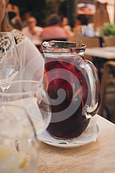 Red wine sangria or punch with fruits and ice in glass. Homemade refreshing fruit sangria on white table in restaurant