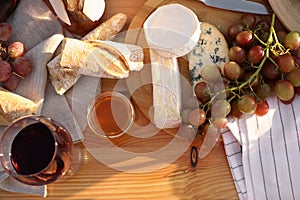 Red wine and snacks served for picnic on wooden table, flat lay