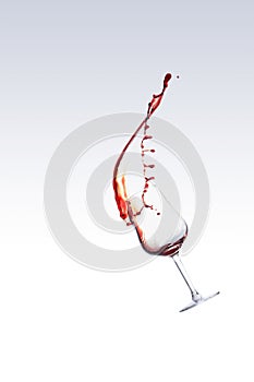 Red wine splashing out of a glass, isolated over white background