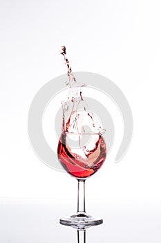Red wine splashing out of a glass, isolated on white
