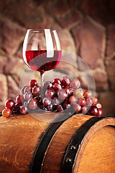 Red wine.Still life with glass of red wine, grapes and barrel.Selective focus.Wine cellar atmosphere.Copy space